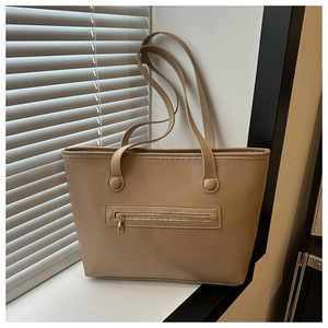 Dettaglio della tasca frontale con zip e della trama premium della borsa tote beige