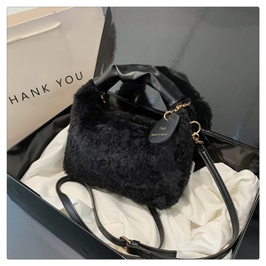 Détail d'un sac à main en peluche noire avec poignées en cuir dans un coffret cadeau