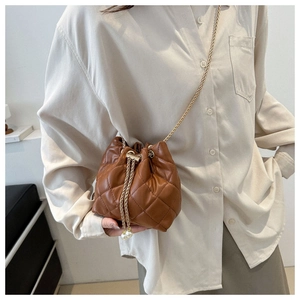 Detail of brown quilted bucket bag with golden chain strap and elegant pearl accents