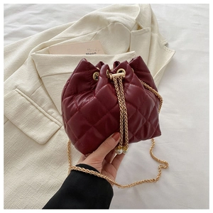 Detail of burgundy bucket bag featuring quilted PU leather and gold chain with pearls