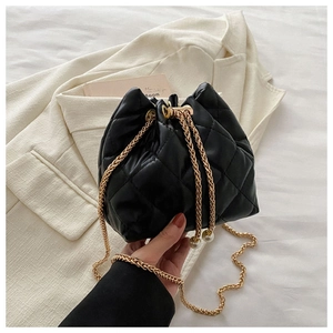 Detail of black quilted bucket bag with gold chain strap and pearl charm accent