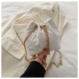 Detail view of white quilted bucket bag with gold chain strap and pearl accents