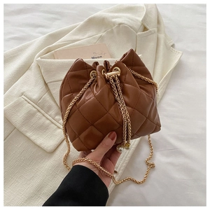 Close-up of brown quilted bucket bag with gold chain strap and pearl drawstring detail