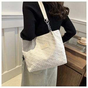 Detail of white tote bag featuring 3D textured grid pattern and metal chain strap