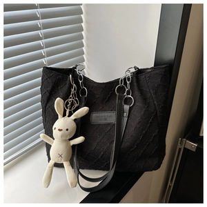 Detail of black tote bag featuring crinkled texture, chain strap and cute rabbit pendant