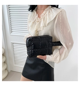 Detail shot of a black quilted down handbag with a puffy nylon texture and sturdy handles