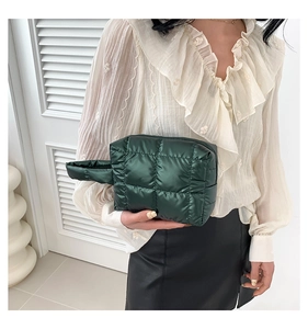 Close-up of a green quilted cotton tote bag held by a model with side handle detail