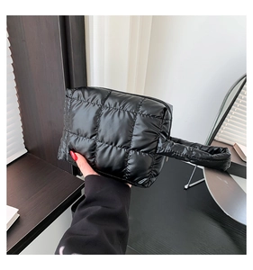 Detail of a black quilted down-textured handbag with a glossy finish and top handle