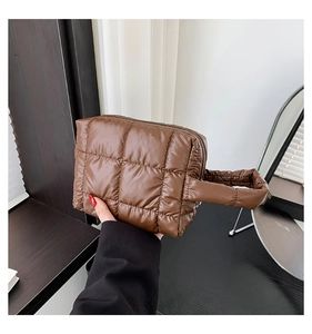 Detail of a dark brown quilted tote bag with soft padded texture and top handle grip