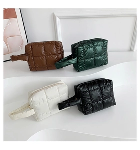 Detailed shot of quilted puffer clutches in brown, green, white and black on minimalist stand