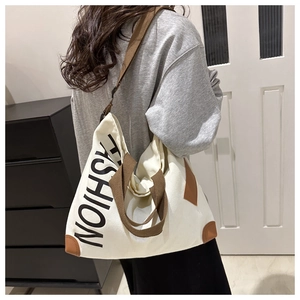 Detail of canvas tote bag with brown straps and vertical black fashion text logo