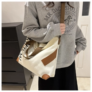 Detail of canvas tote with brown webbing straps and contrast corner protectors