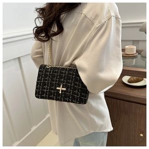 Fashionable black and gold plaid tweed crossbody bag shown on a model in a cafe