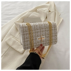 Detail of white and gold tweed texture with a gold turn-lock on a chain crossbody bag