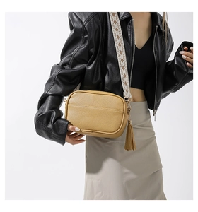 Detail of yellow PU crossbody bag with geometric embroidered strap and tassel