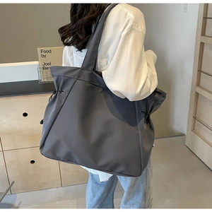 Detailed view of the side drawstring design on a large grey nylon tote bag
