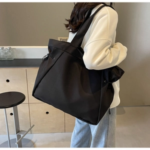 Detailed view of large black nylon tote bag with drawstring and wide shoulder strap