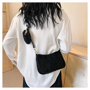 Detail of black corduroy crossbody bag with adjustable strap and small round coin purse