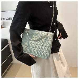 Mint green quilted tote bag with gold chain strap shown on a casual chic outfit