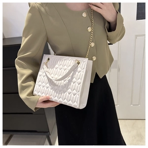 Close-up of white quilted tote bag with gold chain strap and elegant rhombus pattern