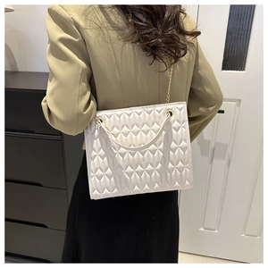 Detail of white quilted tote bag featuring geometric stitching and silver chain strap