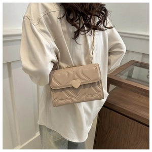 Vista posteriore di una donna con borsa beige trapuntata a cuore e chiusura a cuore in metallo