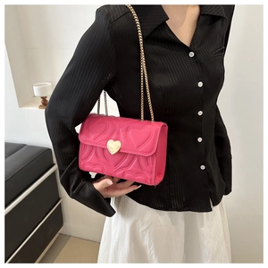 Detail of pink heart-quilted crossbody bag featuring a gold heart-shaped metal lock