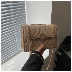 Detail of beige heart-quilted crossbody bag with gold chain strap and metal lock