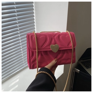 Detail of rose red heart quilted crossbody bag with gold heart-shaped metal buckle