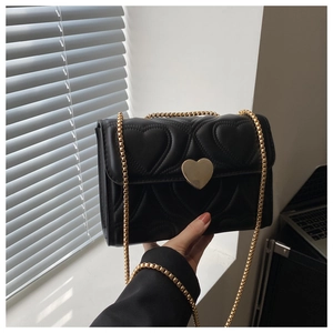 Detail of heart-quilted black faux leather bag with gold heart-shaped buckle and chain