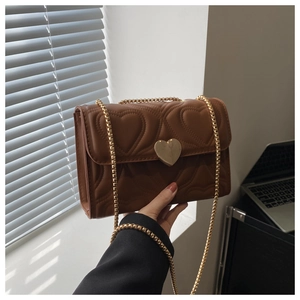 Detail of brown quilted heart bag with gold heart-shaped lock and metal chain strap