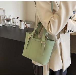Détail du cabas en cuir vert menthe avec finitions dorées porté par un mannequin au café
