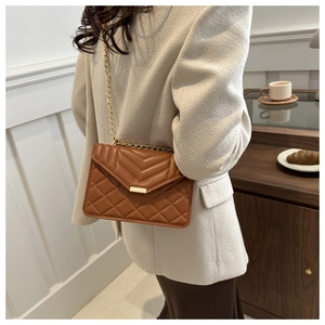 Close-up of caramel quilted leather shoulder bag with gold chain and metal clasp