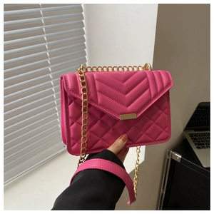 Detail of fuchsia quilted crossbody bag featuring elegant gold chain and V-pattern flap