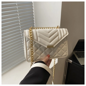 Detailed close-up of white quilted chain crossbody bag with golden hardware and V-pattern