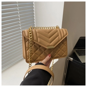 Detail of tan quilted faux leather bag featuring V-shaped stitching and gold chain strap