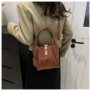 Dettaglio borsa a secchiello vintage in pelle marrone con fibbia dorata lucida