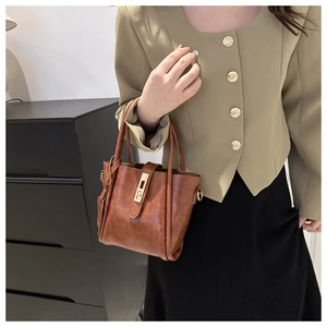 Dettaglio di borsa a mano marrone vintage con chiusura dorata e finitura ruvida