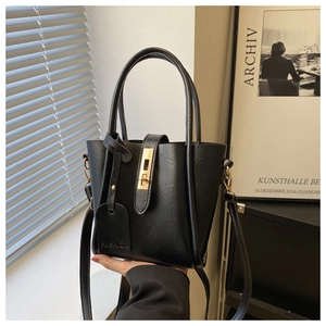 Dettaglio di una borsa a secchiello nera vintage con chiusura dorata e texture in pelle