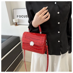 Detail of red crocodile texture handbag with a silver circular metal twist lock buckle
