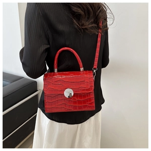 Detail of red crocodile texture handbag with silver metal lock and detachable strap