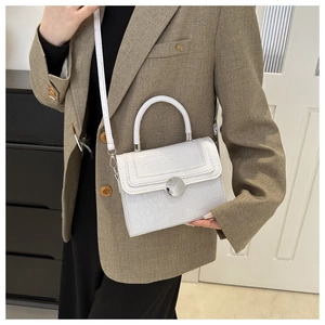 Detail showing the white crocodile-embossed leather texture and large silver round buckle
