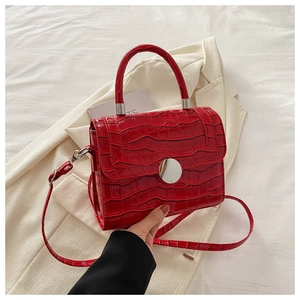 Detail of red crocodile texture handbag with silver round lock and elegant top handle