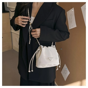 Detail of white bucket bag with drawstring closure and metal chain leather strap