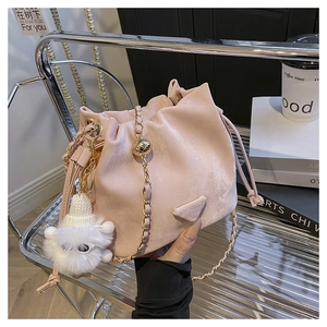 Detail of pink drawstring bucket bag with gold chain strap and plush sheep charm