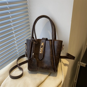 Borsa tote vintage in pelle marrone con chiusura dorata e tracolla su fondo bianco