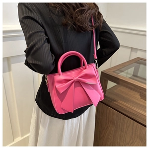 Detail of a bright pink bow handbag showing the large decorative knot and PU leather texture
