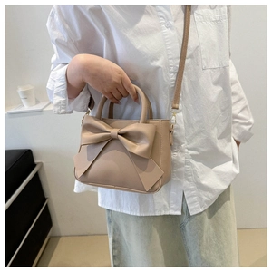 Detail of beige PU bucket bag with large bow and adjustable crossbody strap