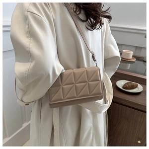 Detailansicht einer beigen gesteppten quadratischen Tasche mit geometrischem Dreiecksmuster