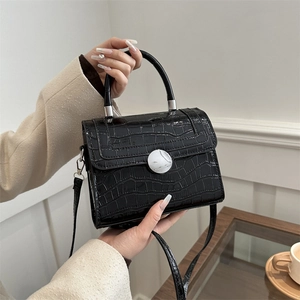 Chic black crocodile embossed handbag with marble buckle on an elegant marble table